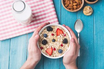 Portrait Of Smiling Teenage Girl Wearing School Uniform In Kitchen Eating Healthy Breakfast