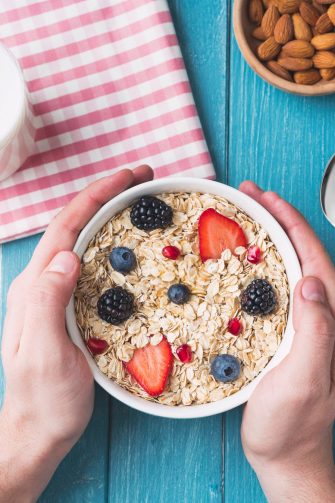 Portrait Of Smiling Teenage Girl Wearing School Uniform In Kitchen Eating Healthy Breakfast