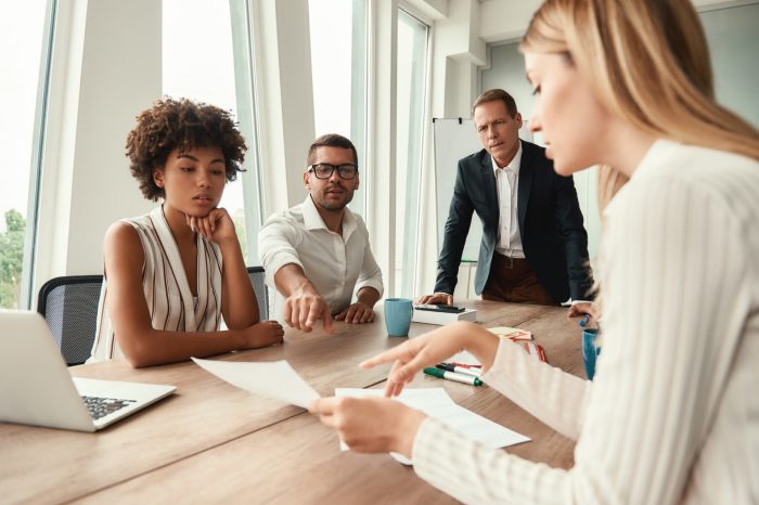 Business meeting. Group of young business people looking at documents and discussing something while sitting at the office table. Brainstorming