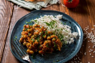 A beautifully plated meal of chickpea curry and rice on a blue plate