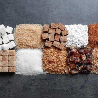 Flat lay composition with different types of sugar on gray background