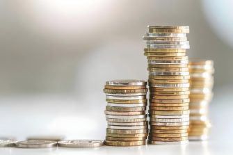 Australian currency held by a woman with braids outdoors in a lush park.