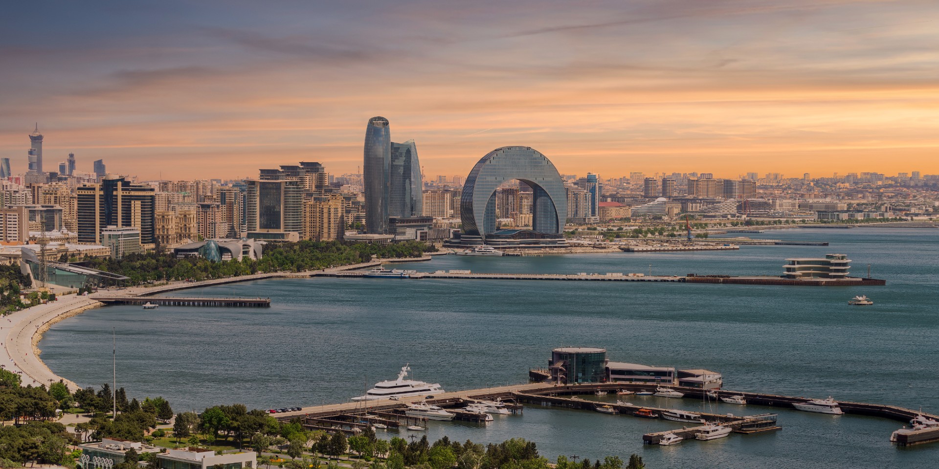 The Crescent Development Project features distinct modern architecture, including the Crescent Hotel, set against a beautiful sunset on the Caspian Sea coast in Baku, Azerbaijan