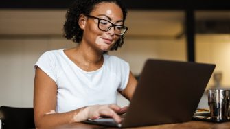 Woman with vitiligo working with laptop while sitting at table in home
