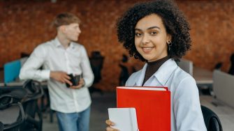 Female student looking at the camera holding a red book
