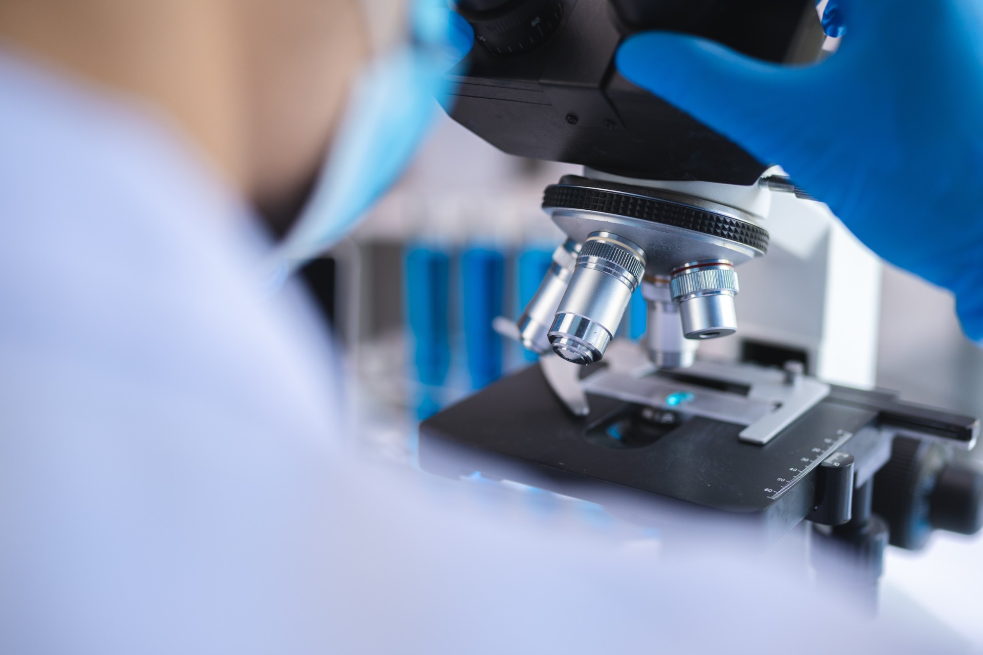 Scientist analyzing microscope slide at laboratory. Young woman technician is examining a histological sample, a biopsy in the laboratory of cancer research