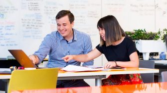 Photograph of a conversation between two adults discussing the disability inclusion plan
