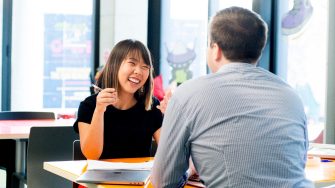Photograph of a conversation between two adults discussing the disability inclusion plan