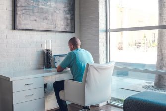 Young man working on laptop at desk with back to camera