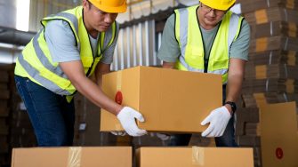 Photo of warehouse workers sharing the lifting of heavy boxes