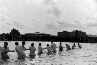 archive image of team of men pulling a rope together through a water