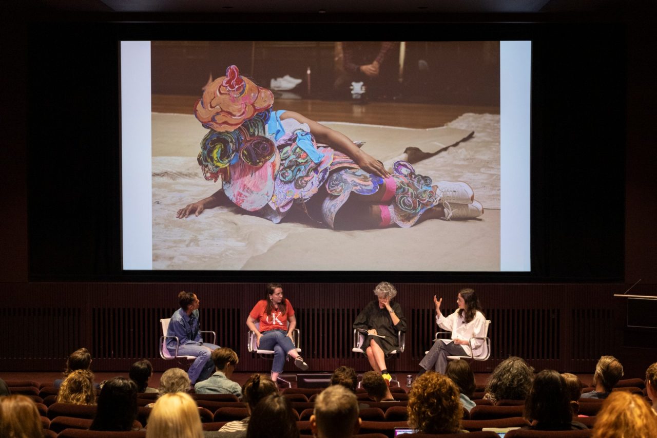 Four people in conversation on stage under a screen