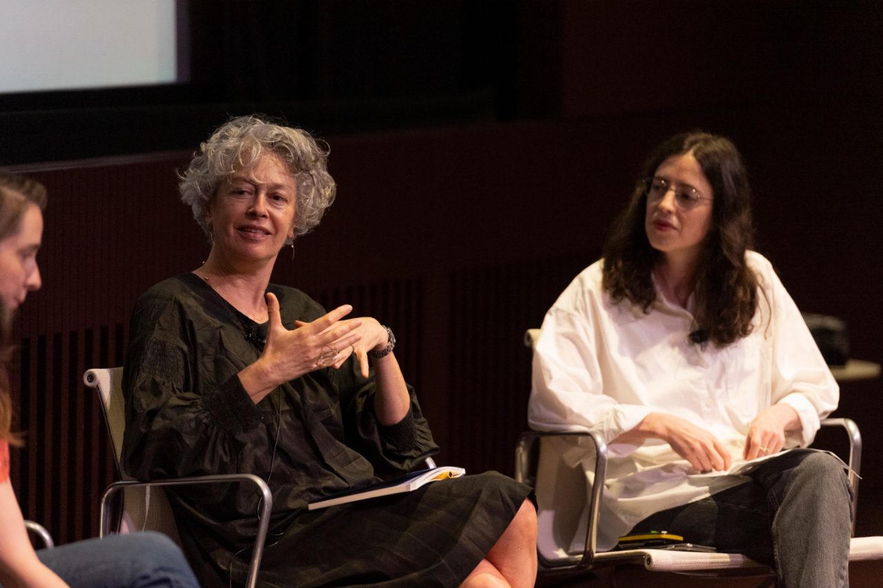 Teo people in conversation on stage and smiling
