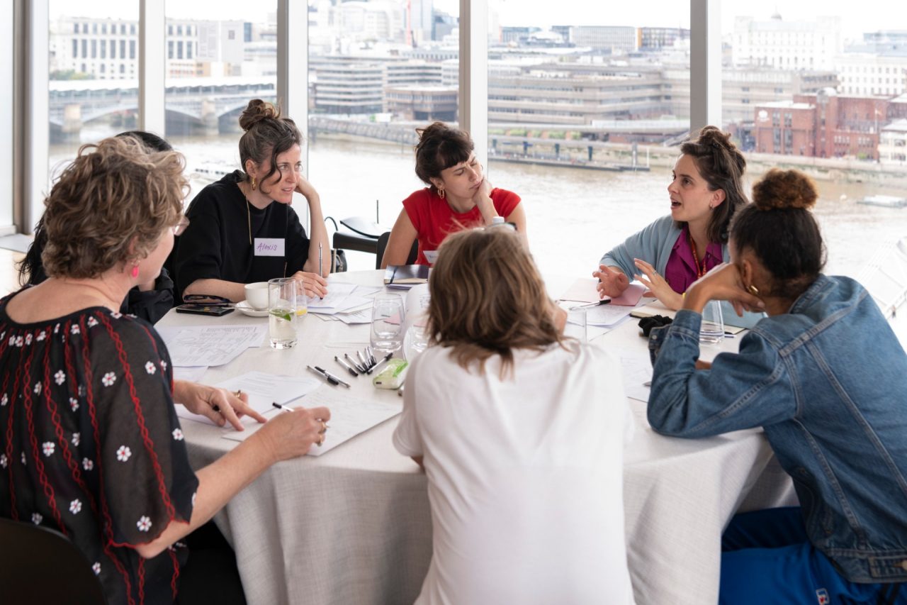Six people around a table in conversation