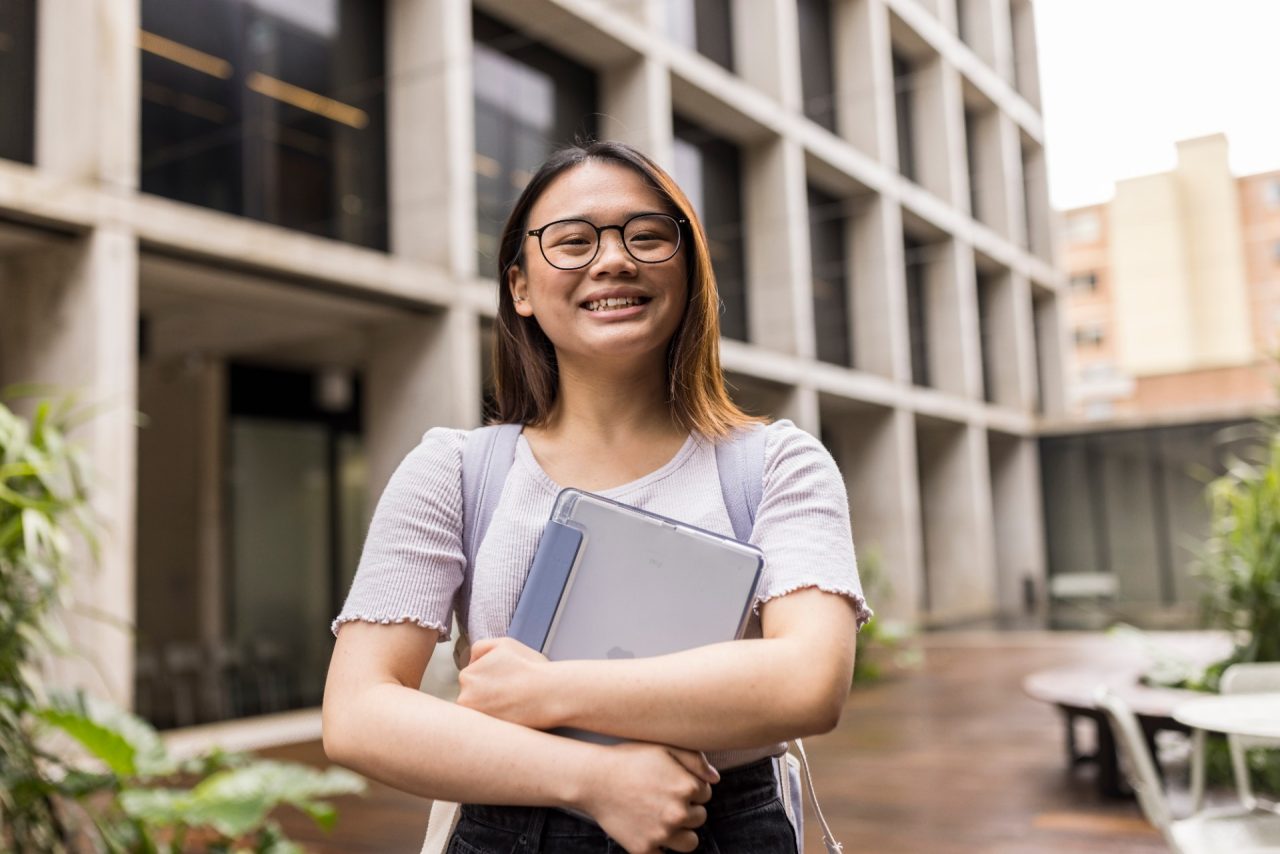 Student (Natalie) walking through the L5 courtyard with backpack and tablet