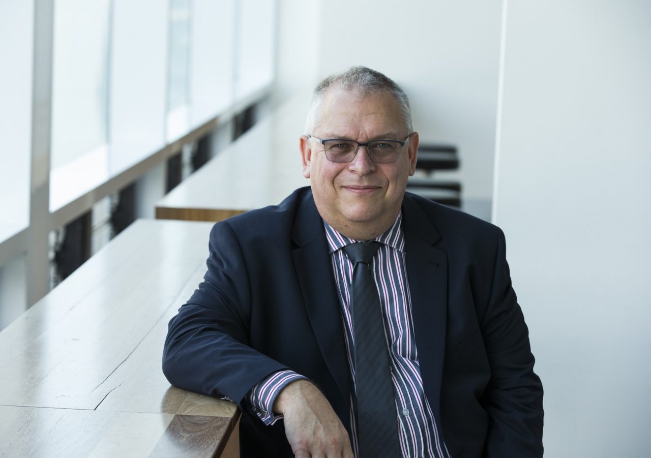 Rob Nicholls smiles while wearing a business suit