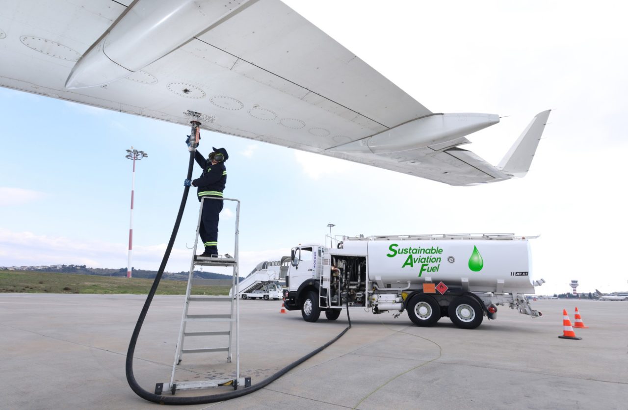 Technician refueling an aircraft with Sustainable Aviation Fuel (SAF) at the airport.